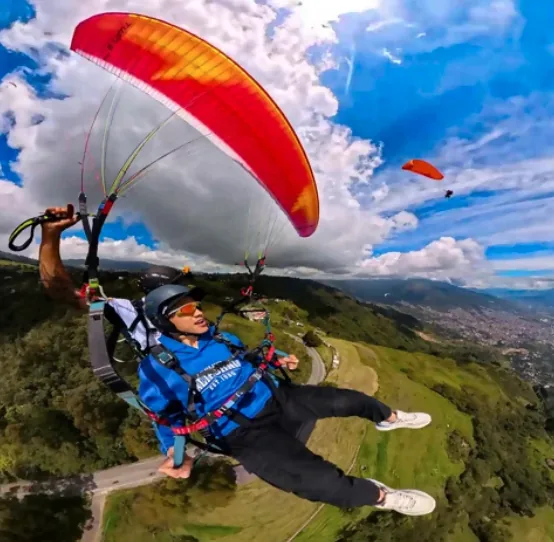 Piloto de parapente sonriendo durante un vuelo tándem sobre Medellín